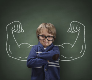 Strong man child showing bicep muscles concept for strength, confidence or defence from bullying